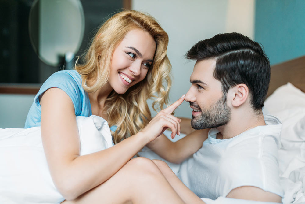 Smiling Girlfriend Touching Boyfriend's Nose when they Wake Up on the Morning
